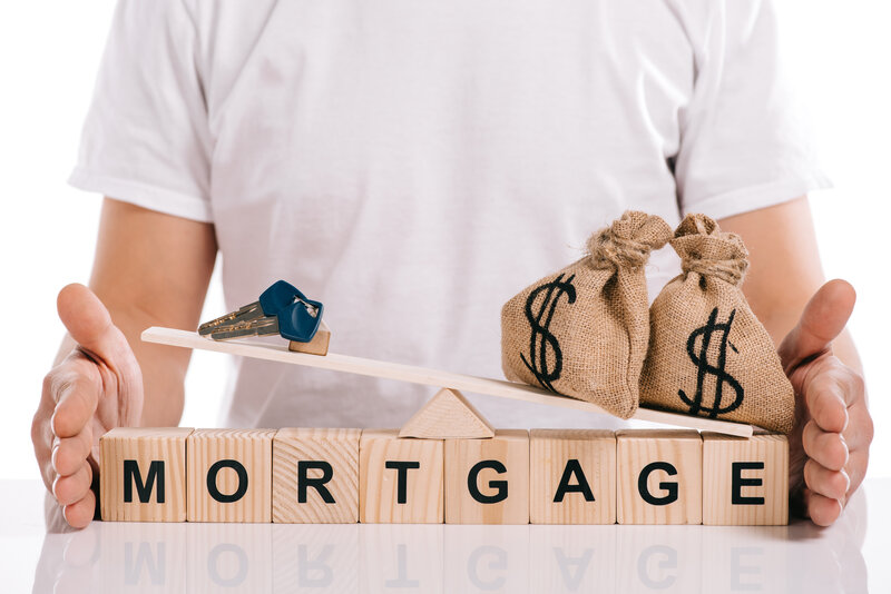 cropped view of man holding scales with moneybags and keys on cubes with mortgage lettering isolated
